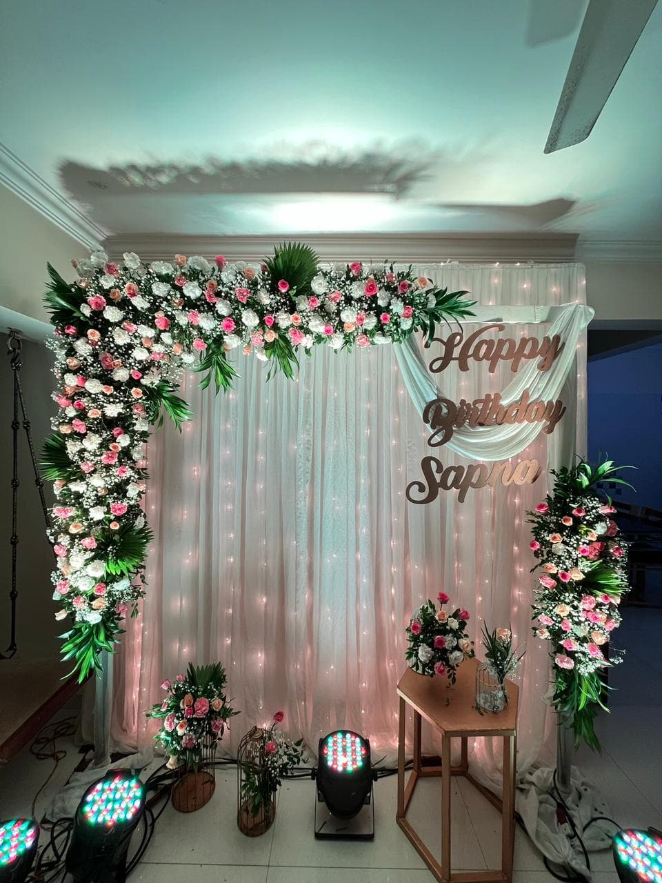 Birthday backdrop with fairy lights, florals, and personalized signage